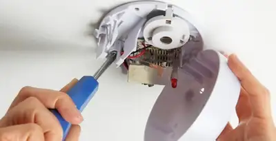 Certified technician wiring smoke detector during installation in Nashville, TN